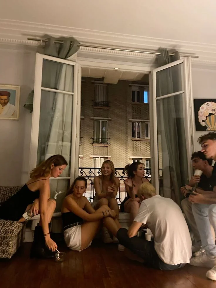 Friends sitting by an open window at night
